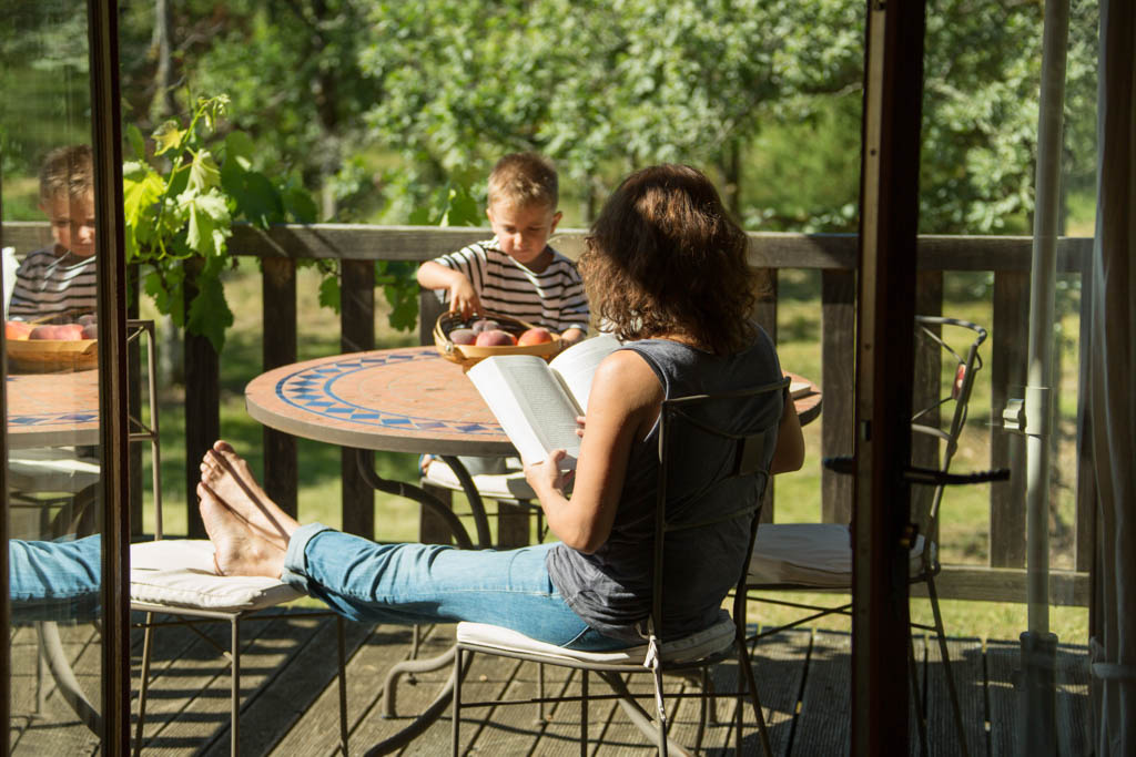 Moments de détente en famille sur la terrasse ensoleillée, entouré de nature verdoyante et paisible