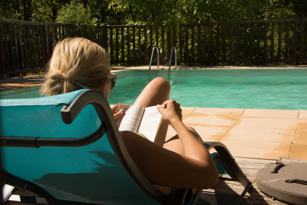 Moment de détente au bord de la piscine, entre lecture et nature verdoyante au cœur du Lot