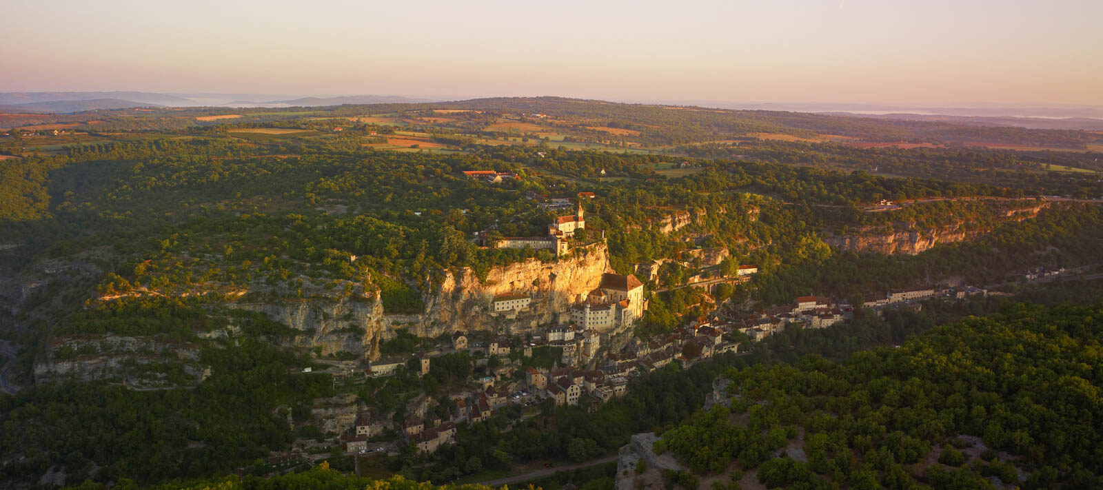Rocamadour majestueux illuminé au coucher de soleil, dominant la vallée verdoyante du Lot depuis ses falaises millénaires
