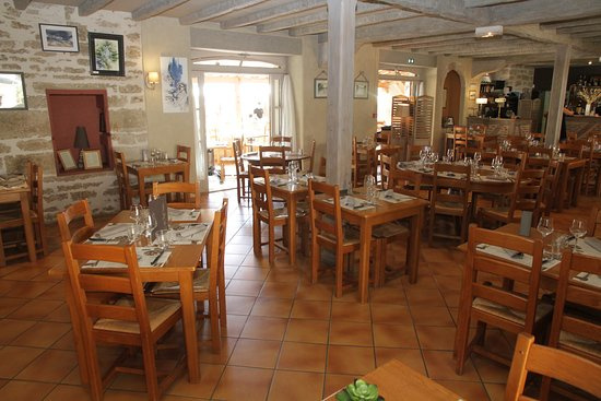 Salle à manger chaleureuse aux murs de pierre et poutres apparentes, où se partagent les repas conviviaux au cœur du domaine