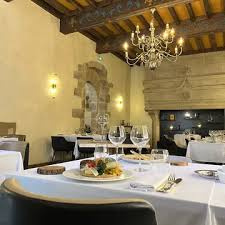 Élégante salle de réception aux poutres apparentes, où pierre et lustre raffiné créent une atmosphère chaleureuse et intemporelle