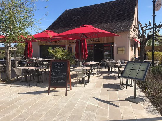 Terrasse ombragée sous parasol rouge, idéale pour savourer un moment de détente en pleine nature lotoise