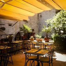 Terrasse couverte baignée de lumière chaleureuse, tables accueillantes entourées de verdure pour vos moments de détente