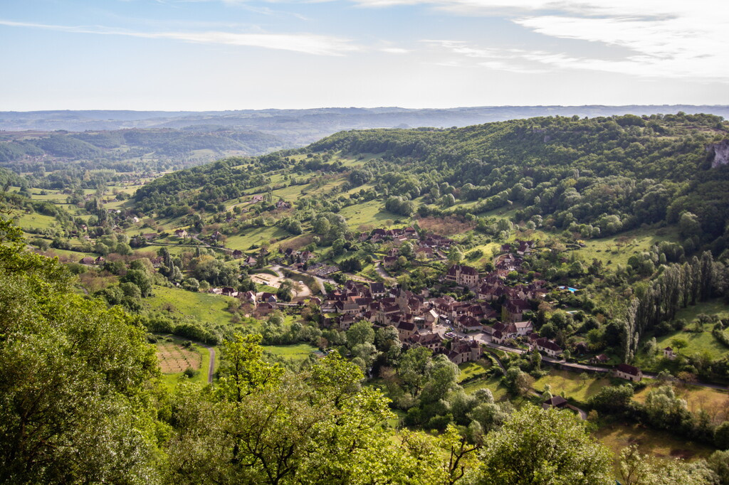 Vue panoramique sur la vallée du Lot : villages pittoresques nichés entre forêts verdoyantes et falaises calcaires, invitation à explorer le cœur authentique du Quercy