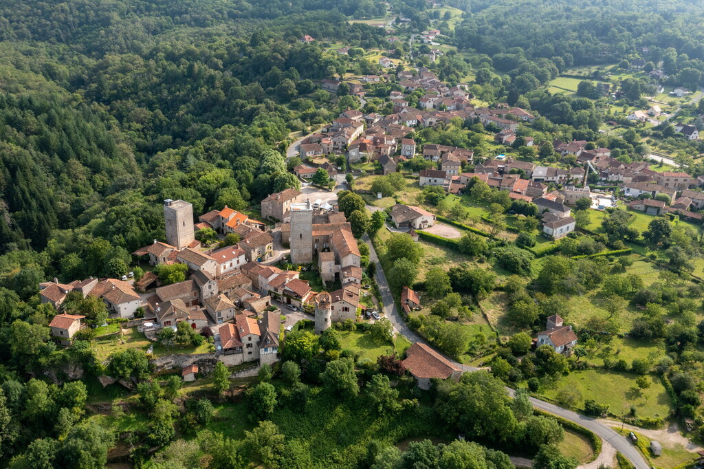 Vue aérienne d'un village médiéval du Lot niché dans la verdure, proche des trésors de Rocamadour et Saint-Cirq-Lapopie